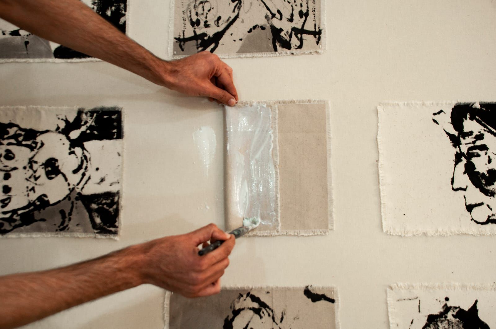 Hands gluing a canvas fragment among ink portraits
